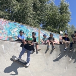 a group of boys sitting on the edge of a skatepark jump